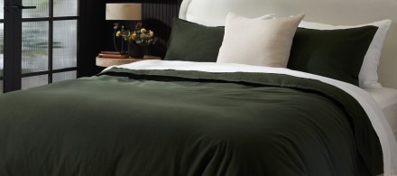 A bed with an evergreen organic corduroy duvet cover set and white sheets