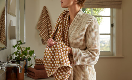 woman in a bathrobe using a tan waffle towel