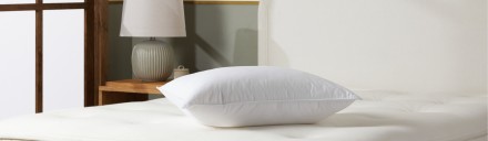 a down pillow resting on top of a mattress