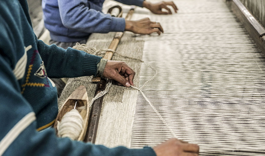 People weaving rugs 