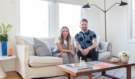 Ariel Kaye and Orlando Soria sitting on a soft inside Ariel Kaye's home.