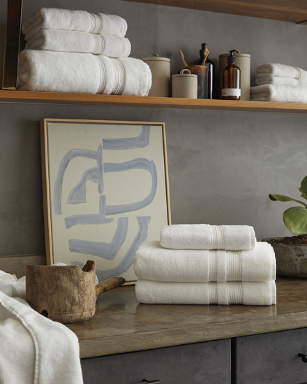 White plus towels neatly stacked on a grey and blue bathroom counter.