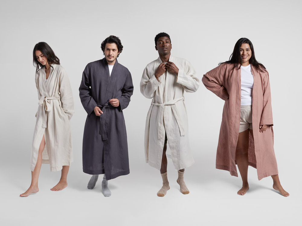 Two men and two women model a linen robe in front of a white backdrop.