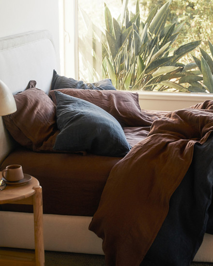 A messy linen bed with dark grey and purple sheets