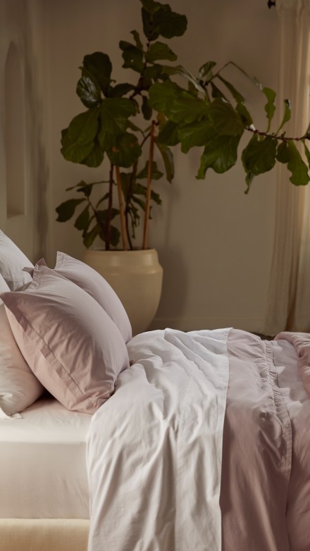 A bed with white and haze cotton percale sheets