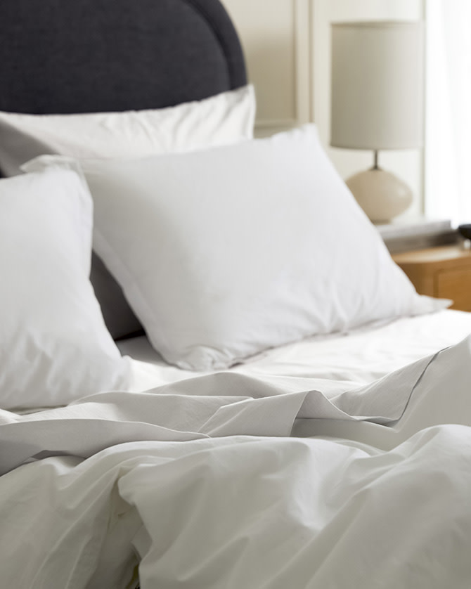 A messy bed with white and light grey mist brushed cotton sheets