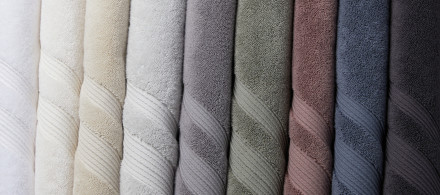 Classic Turkish Cotton Towels hanging in a row: white, cream, bone, mineral, stone, moss, clover, dusk, and charcoal