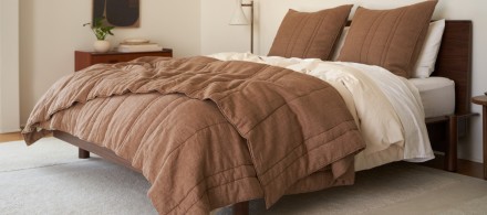 A bed with a mocha patina linen quilt and bone and white percale sheets