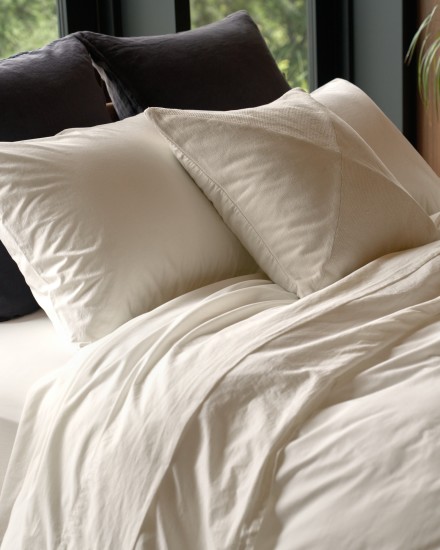 A bed with slate and cream percale sheets