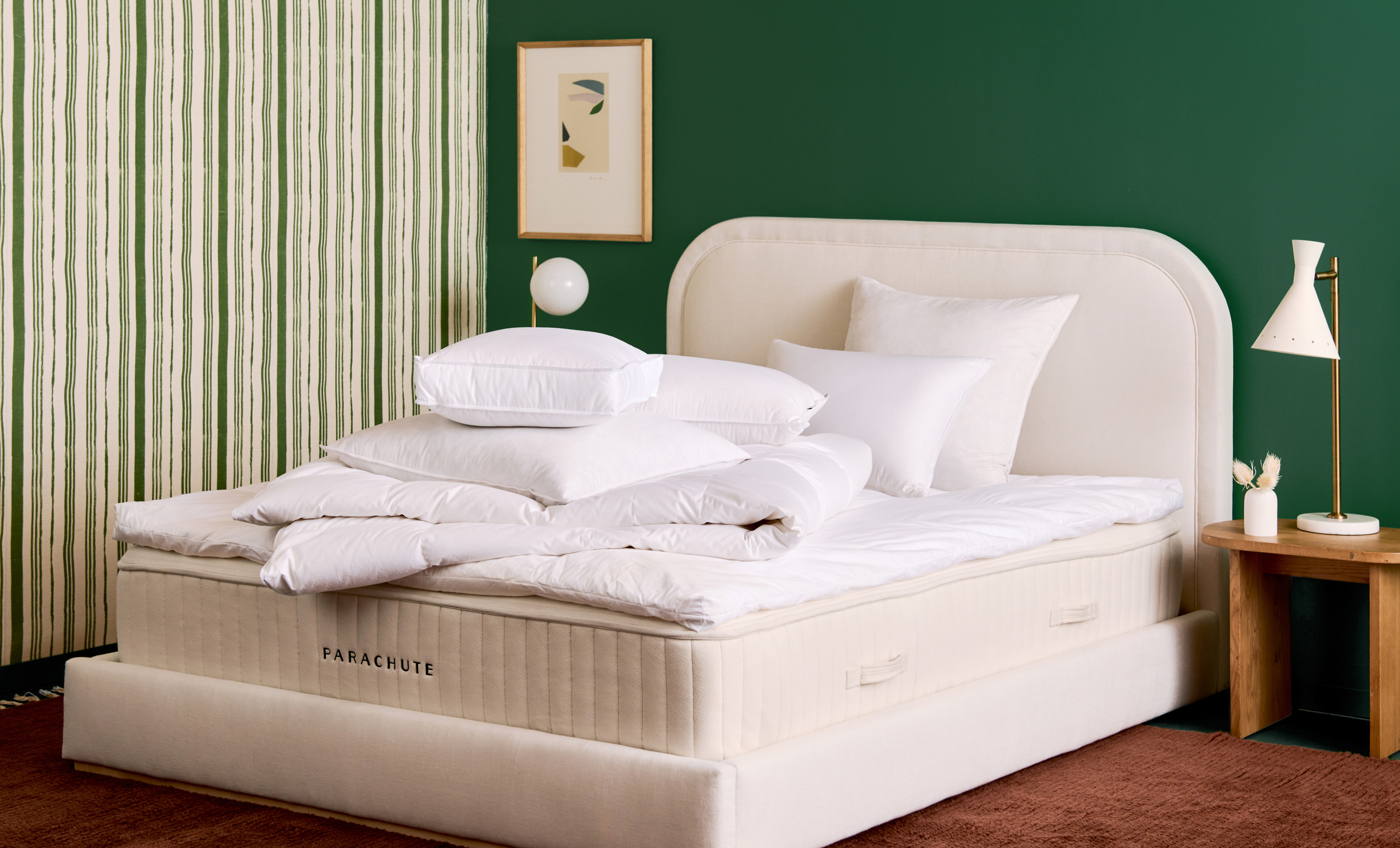 Bare mattress with bare pillows and bedding inserts against a green wall