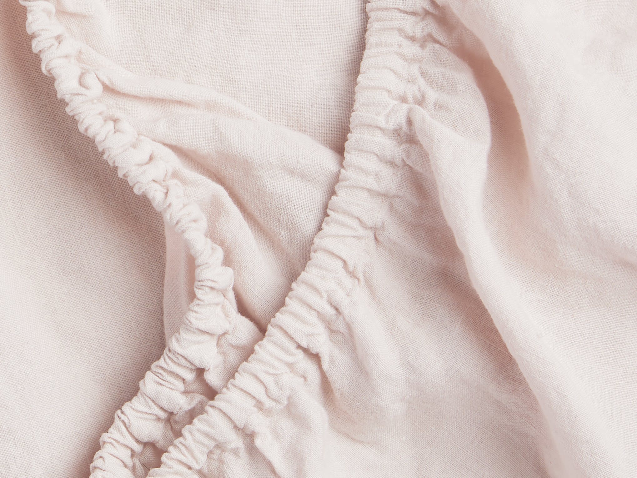 Close Up Of Blush Linen Crib Sheet