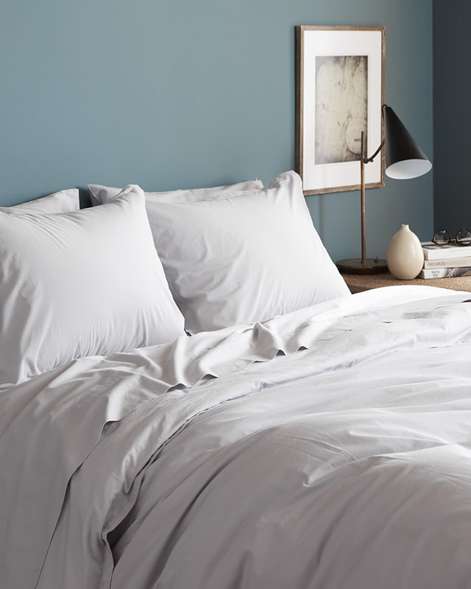 A neat bed with crisp light grey percale sheets
