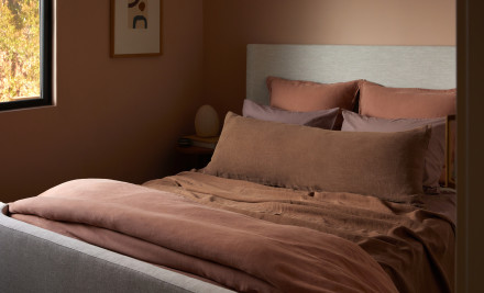 A bed made with various warm-tones of linen sheets