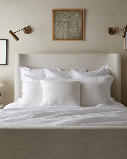 An all-white bed with three neat rows of decorative pillows