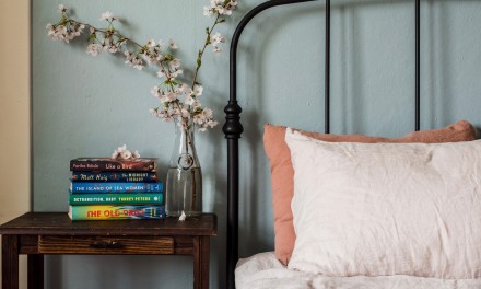 Book stack next to a blush and clay bed. 