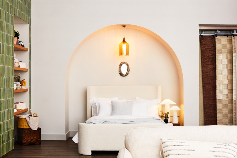 A bright white bed under an archway next to a green-tiled wall