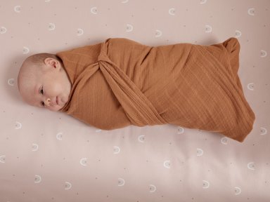 Terra Muslin Swaddle Blanket Shown In A Room