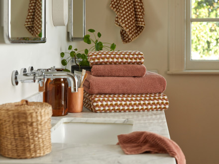 A stack of dusty pink and multicolored towels on a bathroom counter
