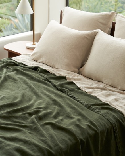 A bed with bone and evergreen linen sheets