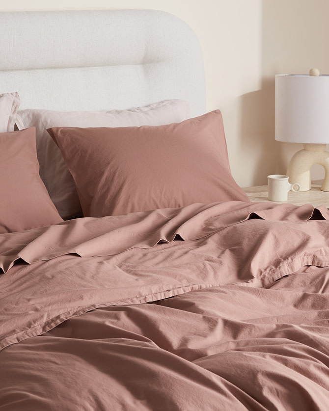 A bed with clay pink percale sheets