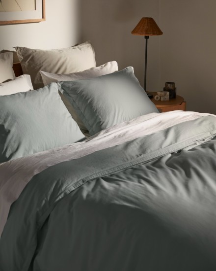 A bed with white and spa percale cotton sheets