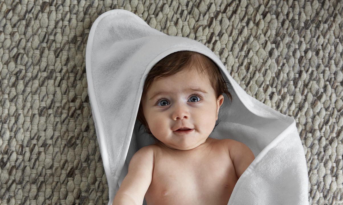 a happy baby using the hooded baby towel