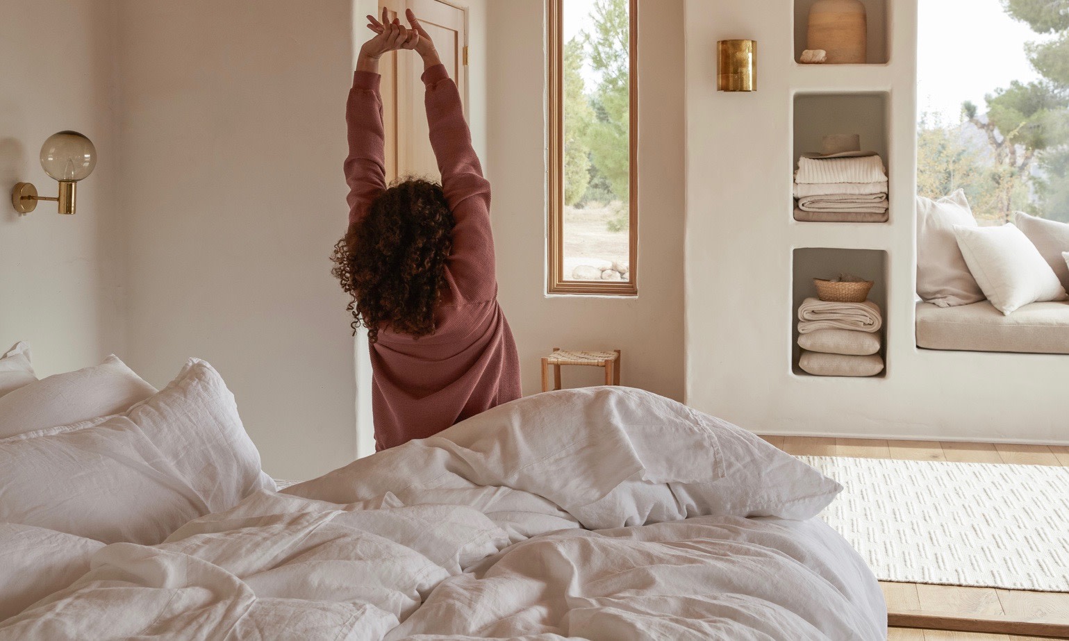 Woman stretching as she gets out of bed. 