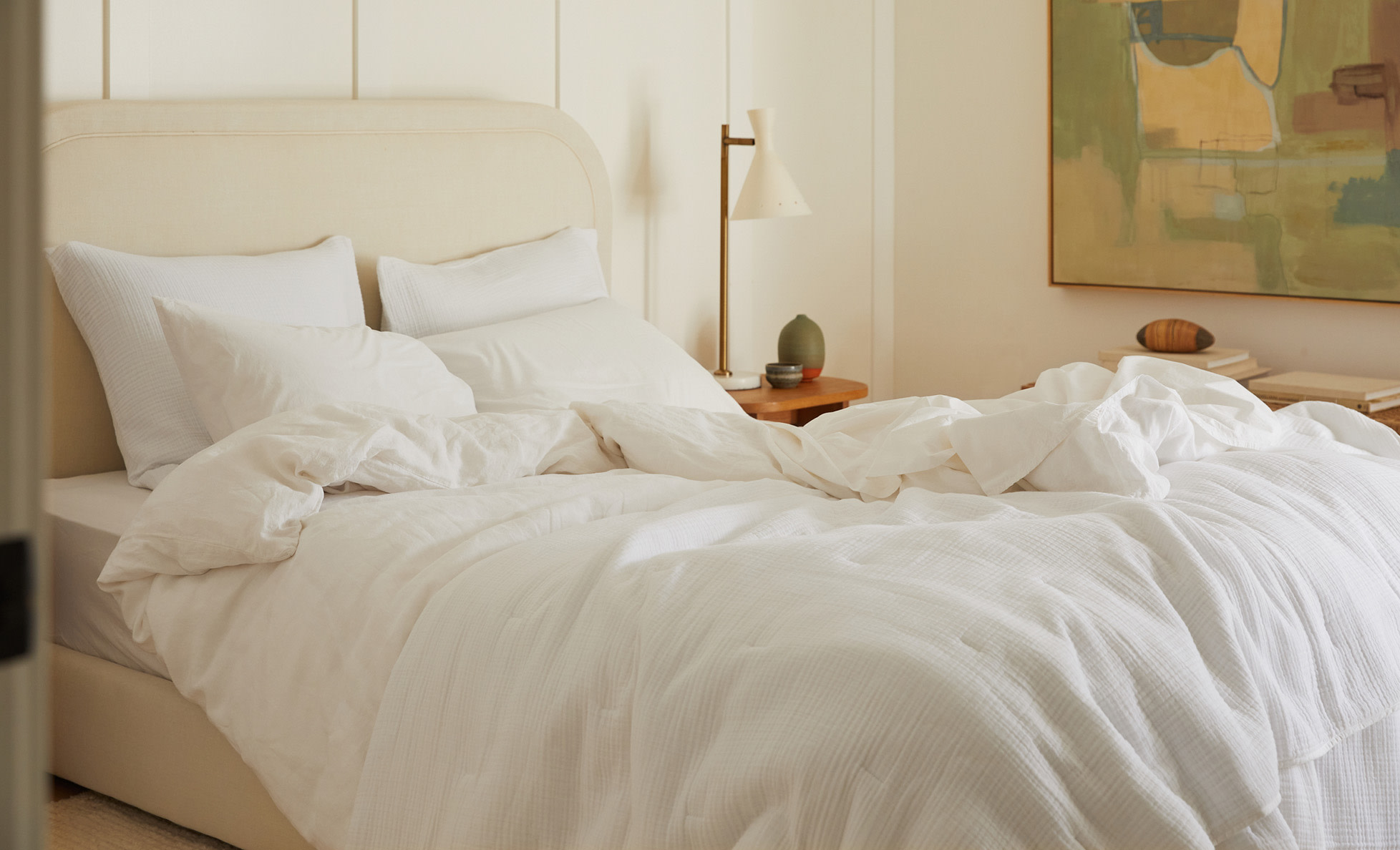 A messy bed with all-white sheets and blankets