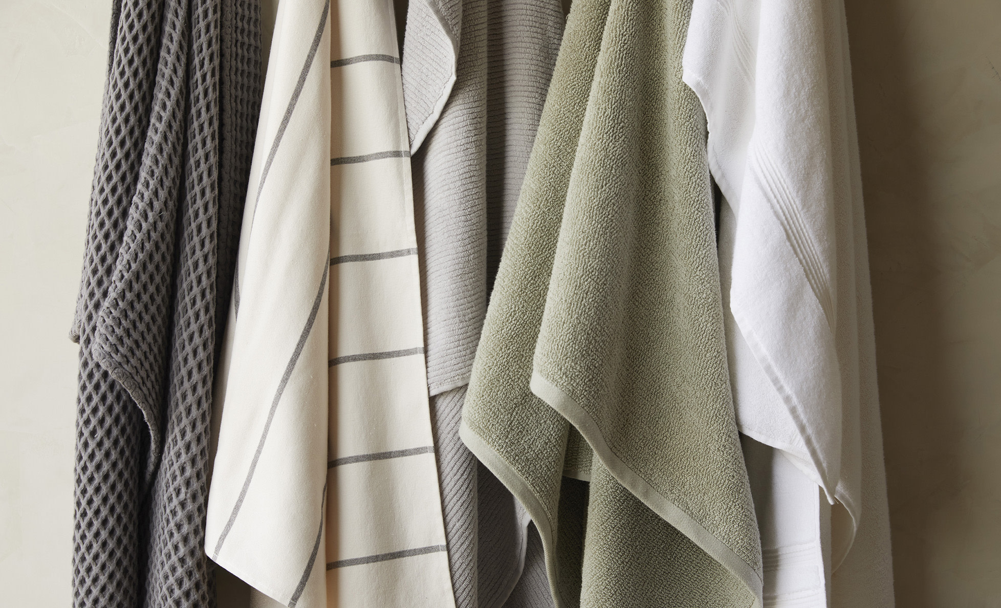 Variety of towels with different colors and textures hanging on hooks