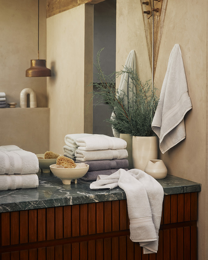 Plush towels stacked on a travertine bathroom counter