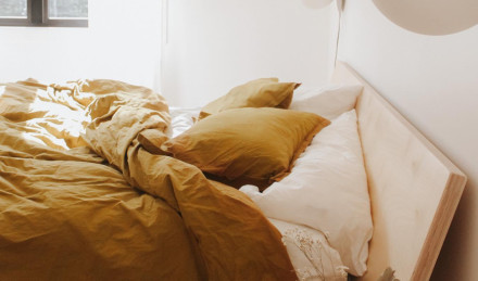 Slept-in Ochre Brushed Cotton Bedding with morning light shining in