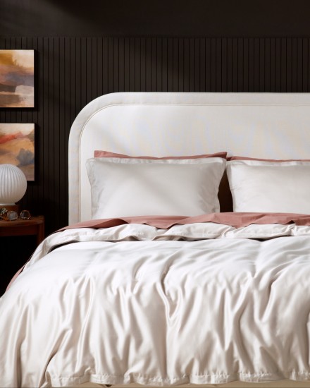 A bed with bone sateen and clay percale sheets