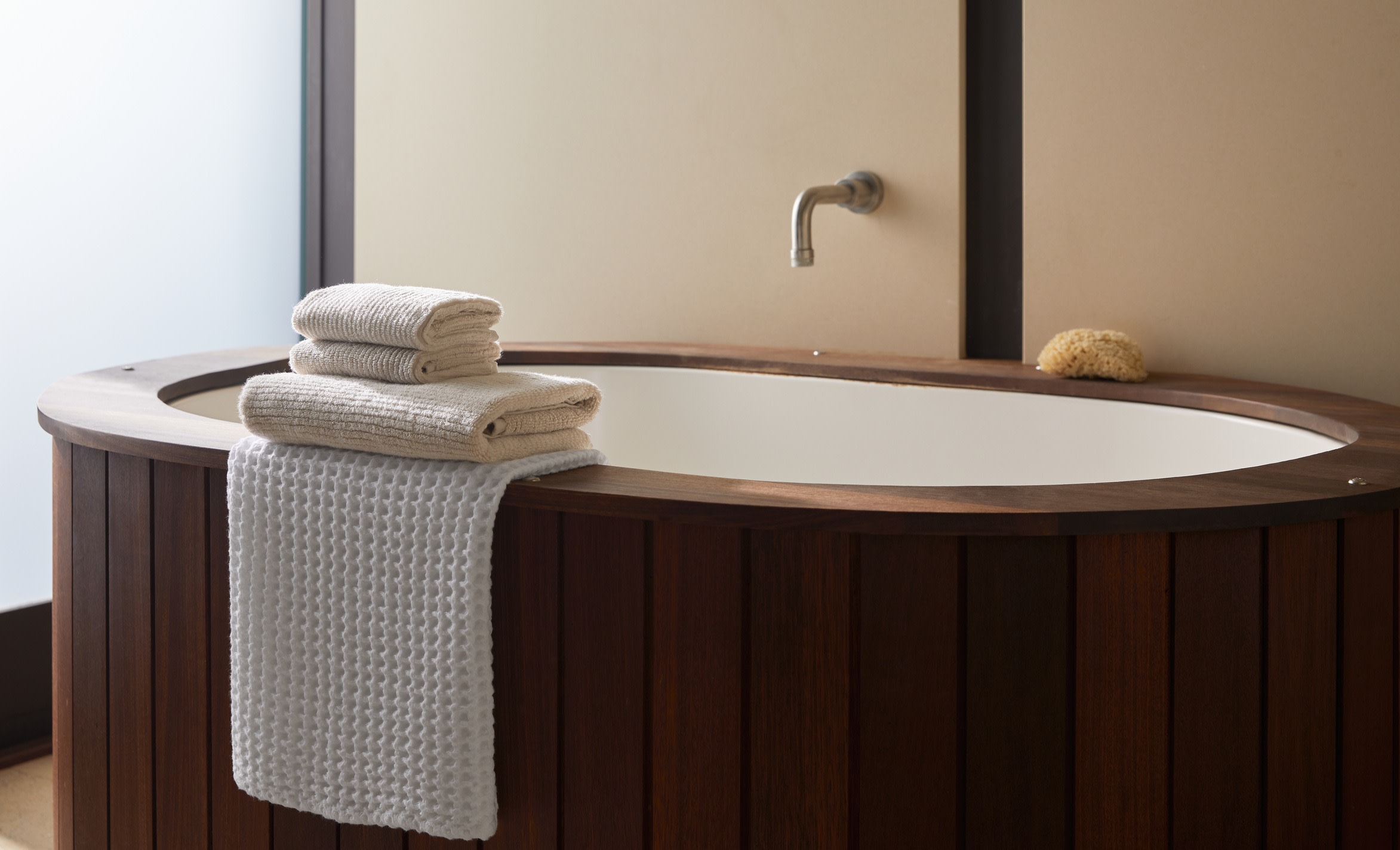 A wood-paneled bathtub with towels stacked neatly on the edge