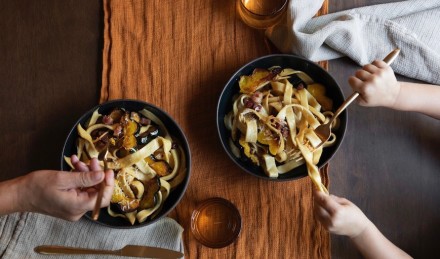 Two people eating pasta on table. 