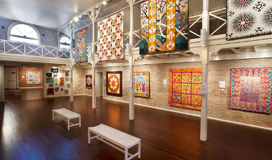 Image of quilts hung in a gallery. 