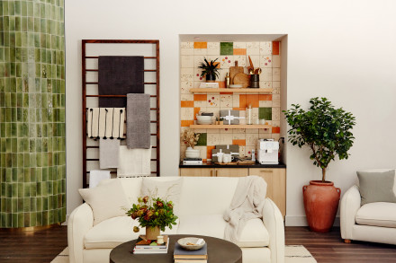 A sofa in front of a wall of shelves with rugs and various bedding placed neatly and artfully 