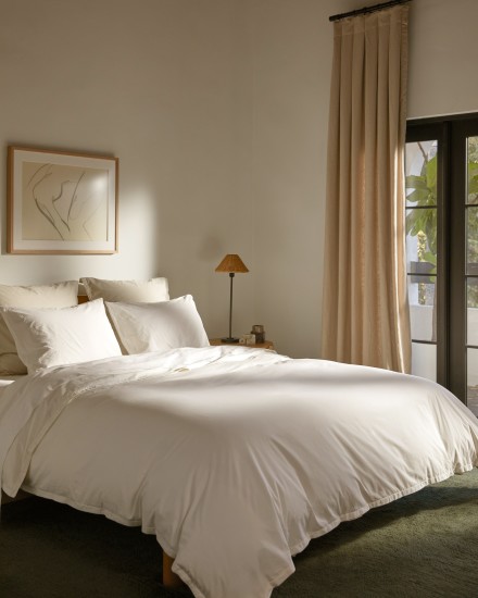 A bed made with crisp white cotton percale sheets 