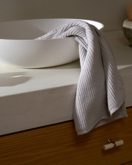 Light grey soft rib towel hanging nicely over the edge of a sink in a bathroom