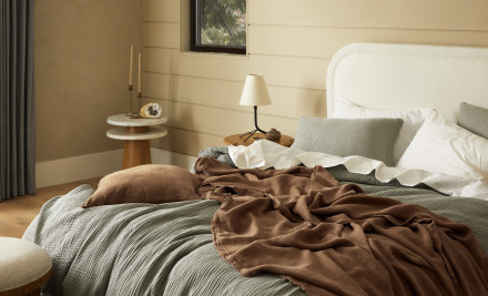 A messy bed with moss green and pecan brown bedding