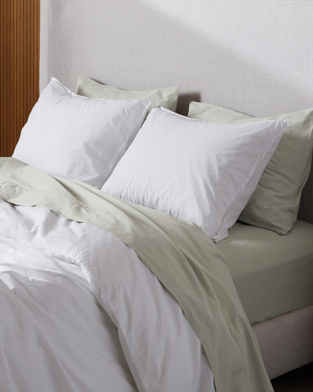 A neat bed with white and willow organic cotton sheets