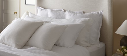A bed with rows of white decorative pillows