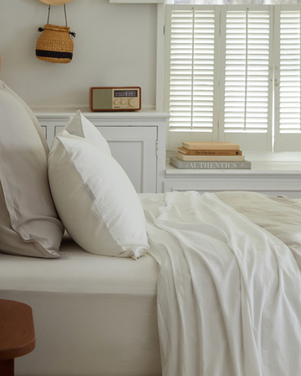 A neat bed with white and cream sateen sheets