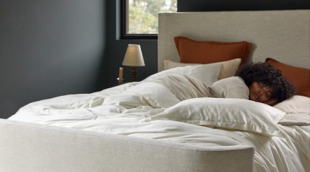 A person sleeping in a cozy bed with cream sateen sheets