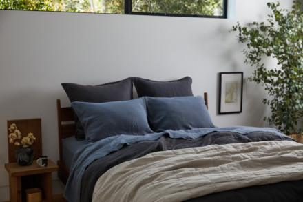 Dusk colored sheeting on a made bed paired with coal linen