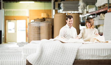 Two people touching a mattress. 