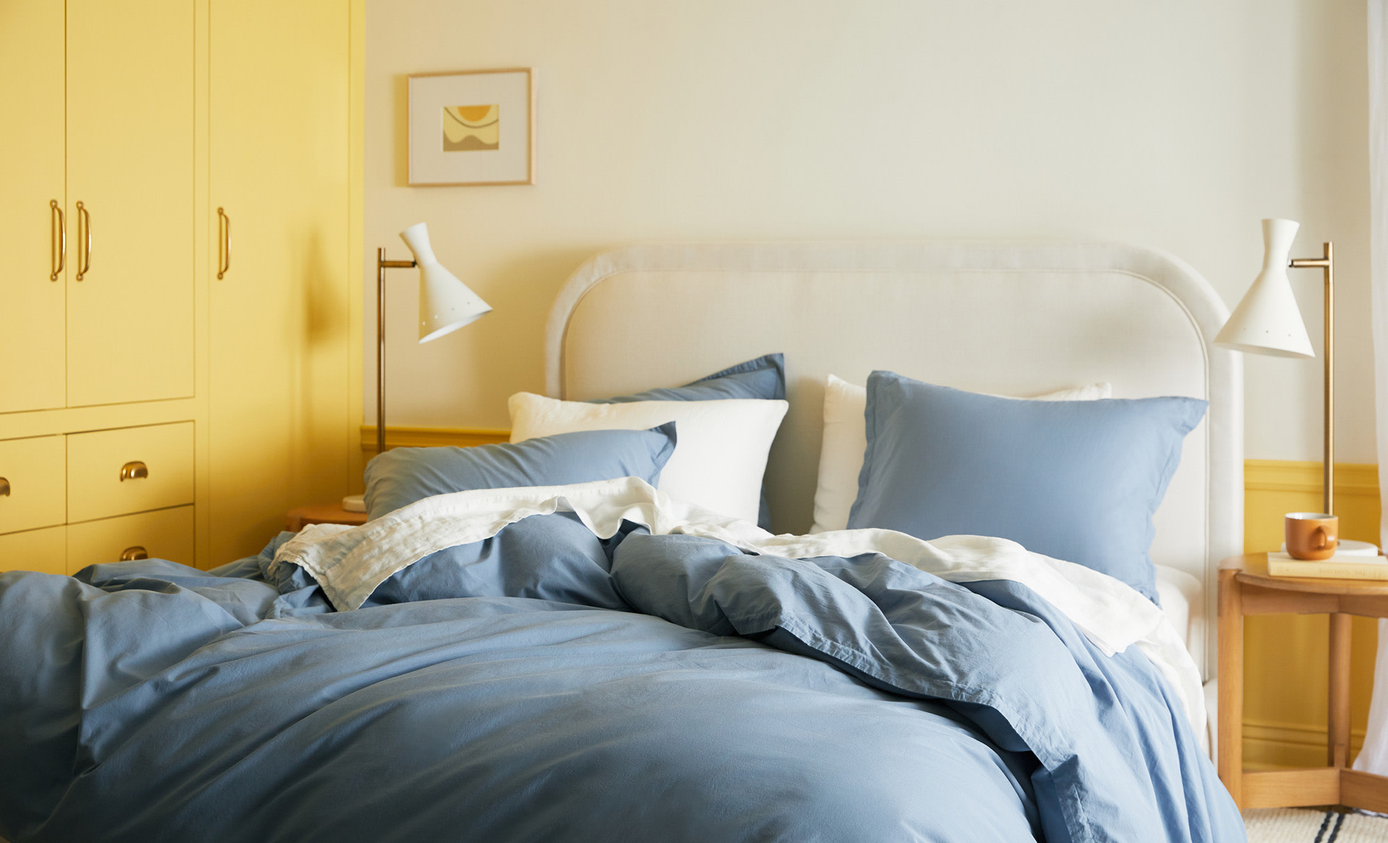 A bright blue bed with modern table lamps