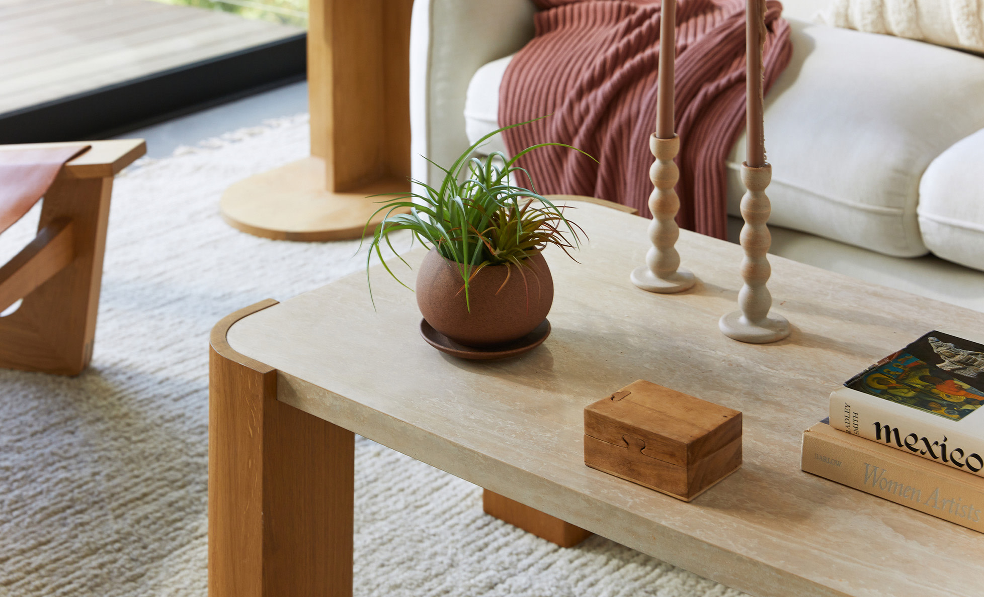 Close-up of a travertine coffee table with a potted plant and candlesticks on top