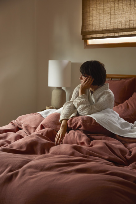 A person lounging in a bed with canyon linen sheets