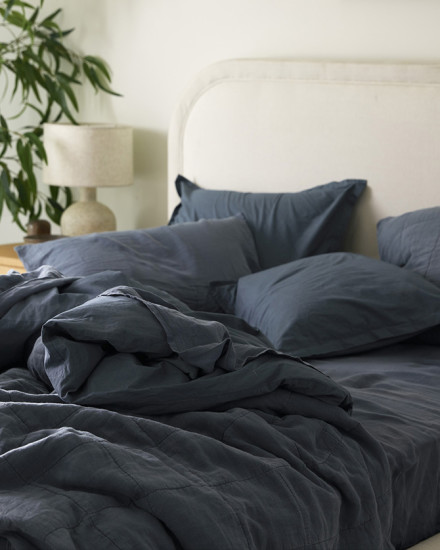 A messy bed with dusk blue brushed cotton sheets