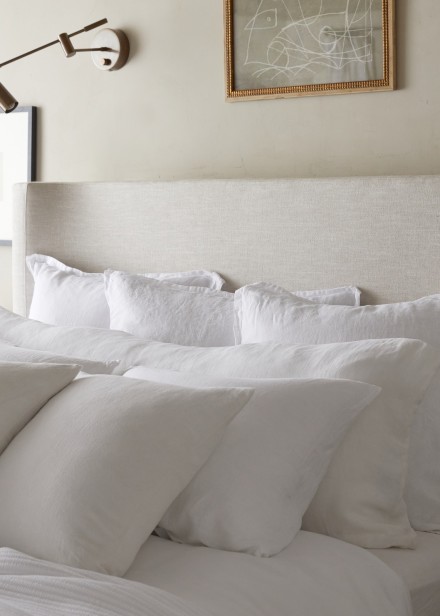 A plush bed with all white bedding and rows of pillows